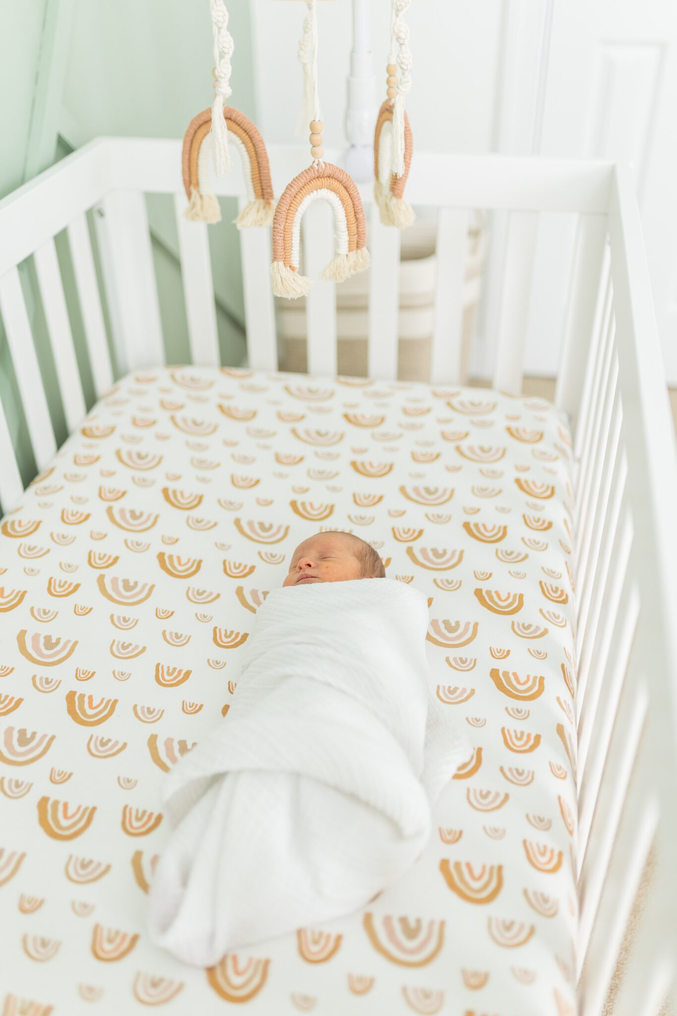 hawaii newborn photography by alison bell photographer. just baby in the crib swaddles with mobile hanging over