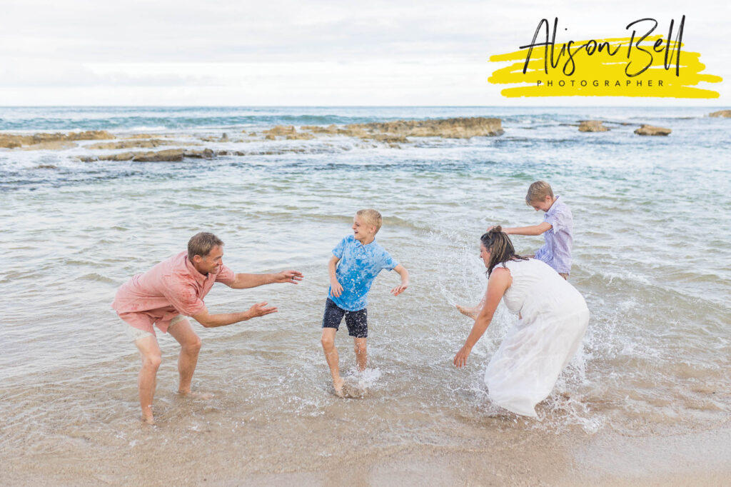 family splashing int water paradise cove beach, ko olina, oahu