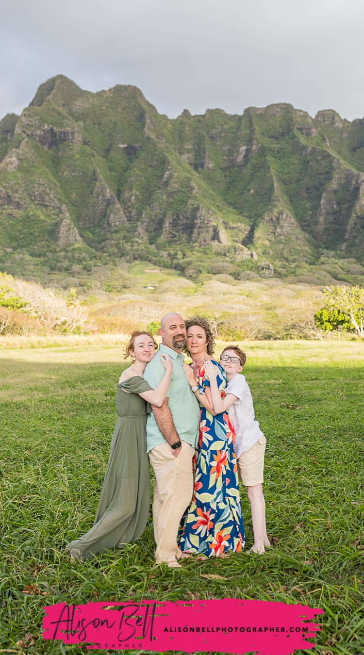 Family posing together in a grassy field with the Koʻolau Mountains in Oahu, Hawaii. Photography by Alison Bell, photographer in Hawaii.
