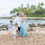 Family walking and playing together on a sandy beach with rocky tide pools and palm trees at Ko Olina in Oสปahu, Hawaii. Photography by Alison Bell, photographer in Hawaii.